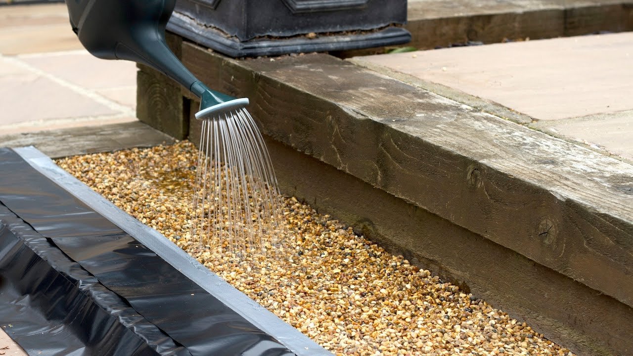 Resin binder being applied to the base before stone is broadcast in a resin bonded gravel system