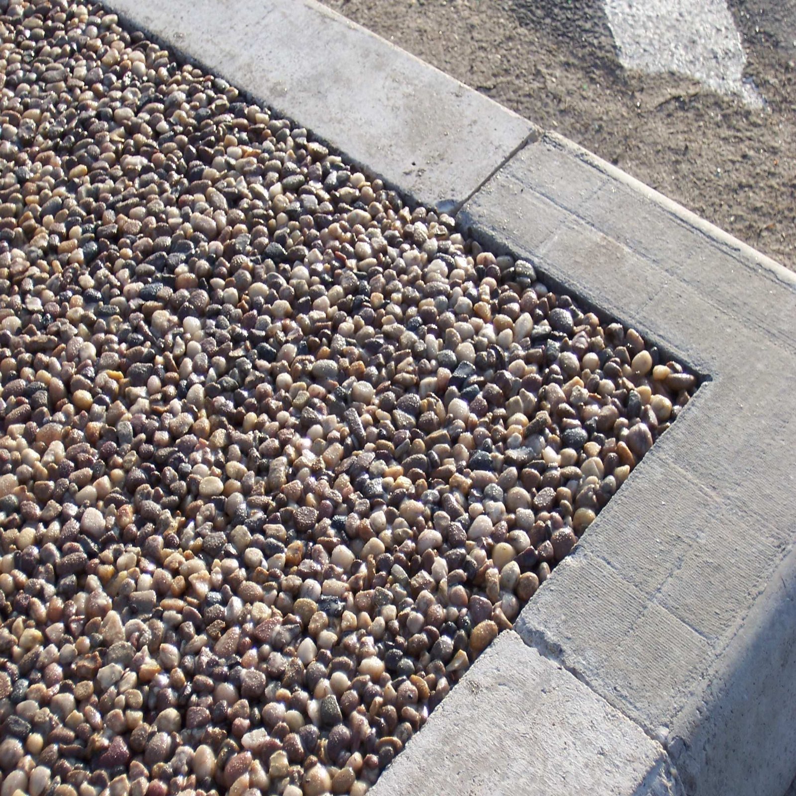 Close-up of a textured resin bonded gravel surface beside a paving edge