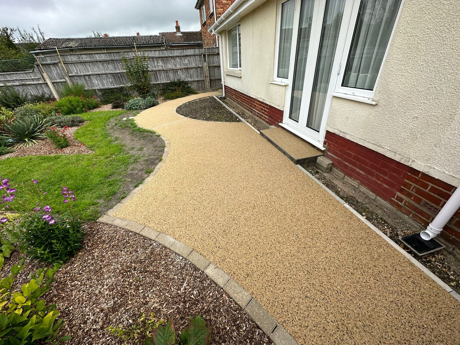Resin patio installation showing smooth transition to lawn